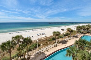 A beach resort with a pool, lounge chairs, and a pier in the background. - 401E Beach Service Included! End Unit! (Panama City Beach)