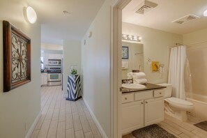 A bathroom with a toilet, sink, and shower. There is a mirror above the sink and a towel rack. The floor is tiled, and there is a rug in front of the toilet. - 401E Beach Service Included! End Unit! (Panama City Beach)