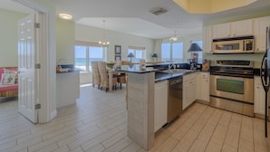A modern kitchen with white cabinets, stainless steel appliances, and a large island. - 401E Beach Service Included! End Unit! (Panama City Beach)