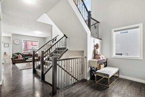 Una sala de estar moderna con una escalera, un banco y una ventana con persianas.