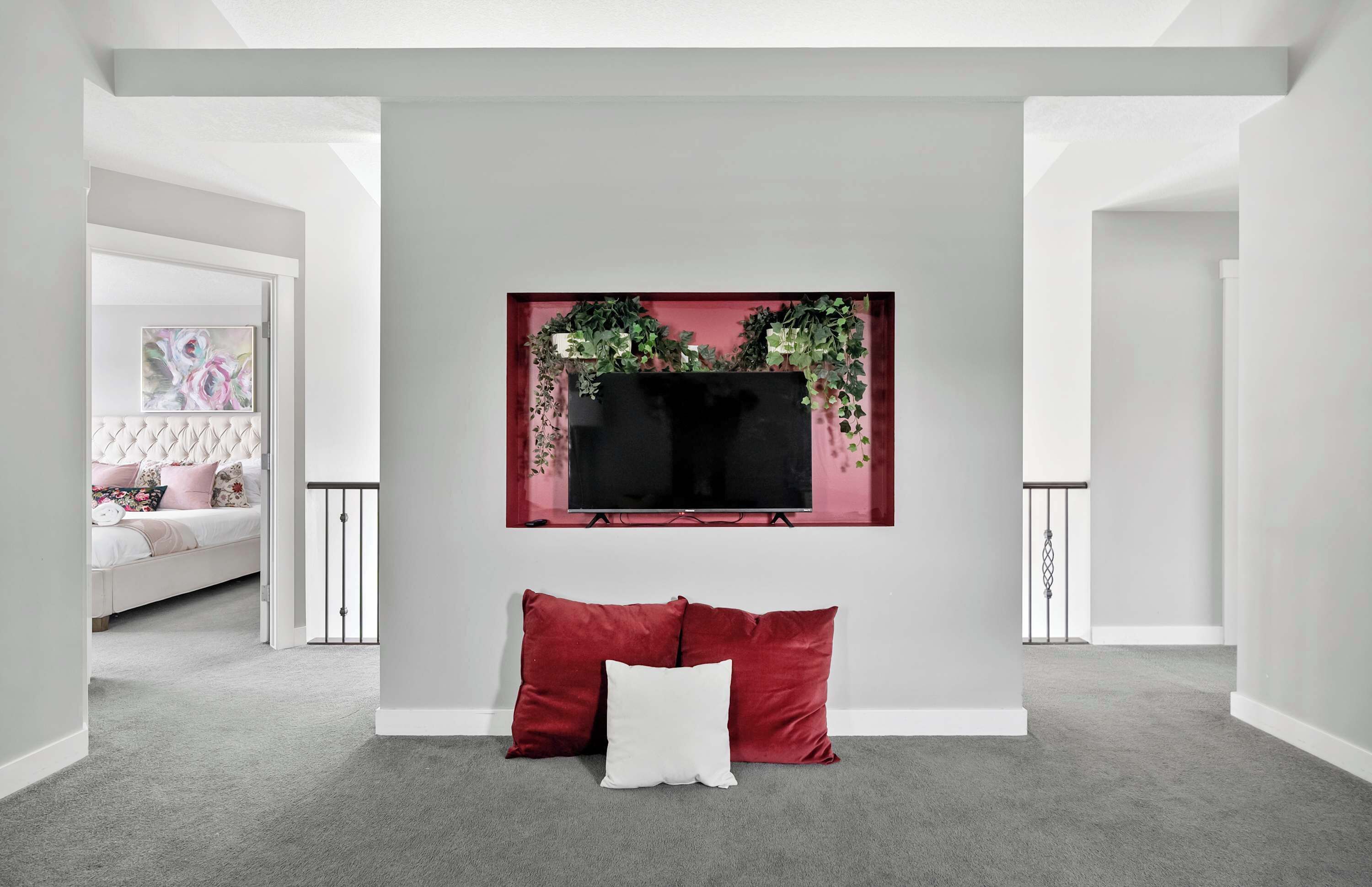 Ein modernes Wohnzimmer mit einem an der Wand befestigten Flachbildfernseher, einem roten Sofa und einem weißen Kissen.