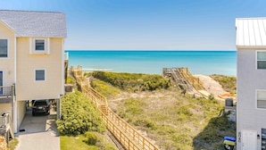 A beachfront property with a wooden staircase leading to a sandy area, a clear view of the ocean, and a building with a white facade. - Dune Just Fine - Gorgeous 5BR Home - Pool, Elevator, Porches & More! (Surf City)