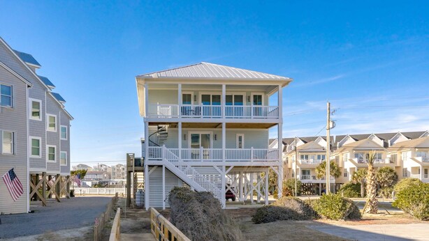 A two-story beachfront building with a balcony, a staircase, and a view of the ocean. - Dune Just Fine - Gorgeous 5BR Home - Pool, Elevator, Porches & More! (Surf City)