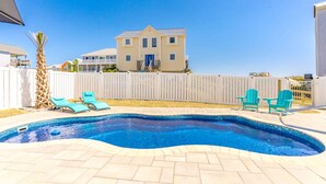 A swimming pool with a tiled deck, two lounge chairs, and a white fence. - Dune Just Fine - Gorgeous 5BR Home - Pool, Elevator, Porches & More! (Surf City)