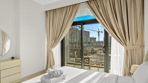 Une chambre d’hôtel avec un grand lit, une table de chevet, un miroir et une vue sur un chantier de construction par la fenêtre.
