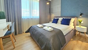 A modern hotel room with a large bed, a desk, and a chair.