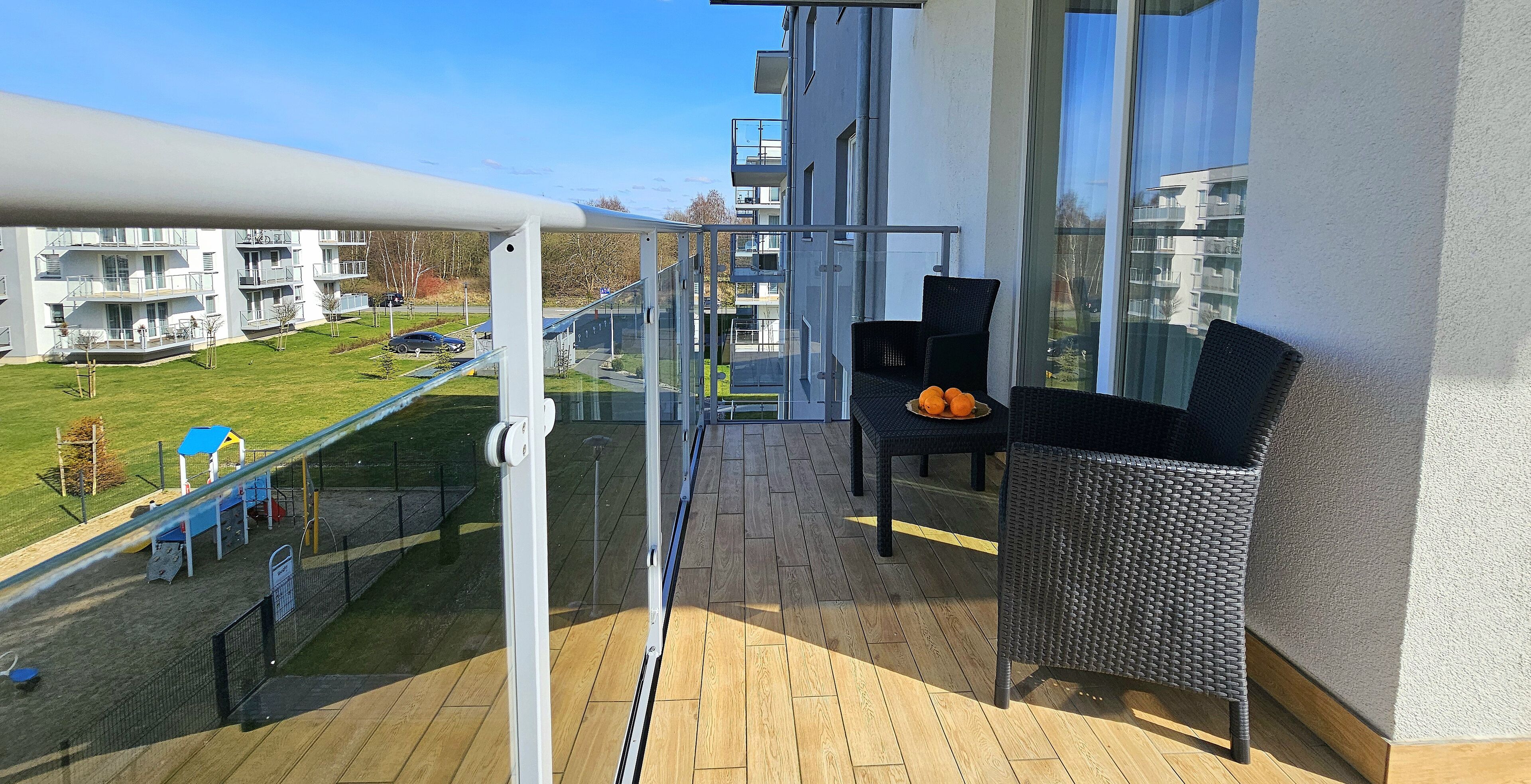 Ein Balkon mit Blick auf einen Spielplatz und Wohnhäuser.