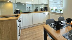 A modern kitchen with white cabinets, a wooden countertop, and a dining area with a table and chairs.
