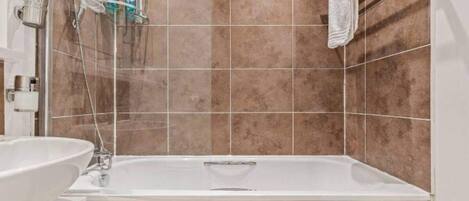 A bathroom with a bathtub, a sink, and a shower area.