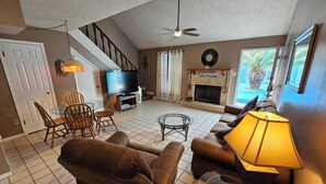 A living room with a fireplace, a television, and a staircase.