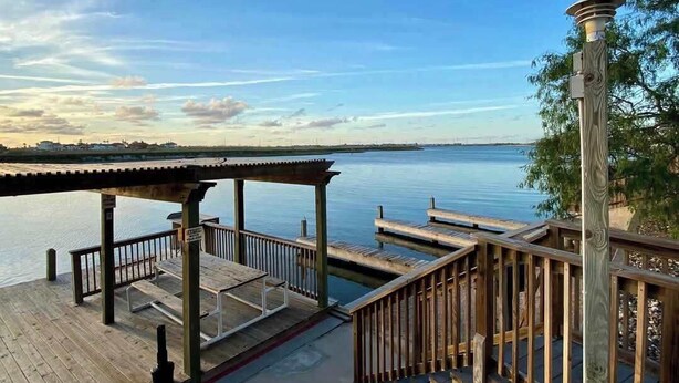 A wooden dock extending into calm water with a gazebo and a lamp post.