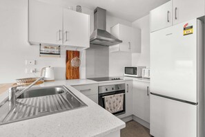 A modern kitchen with white cabinetry, stainless steel appliances, and a microwave.