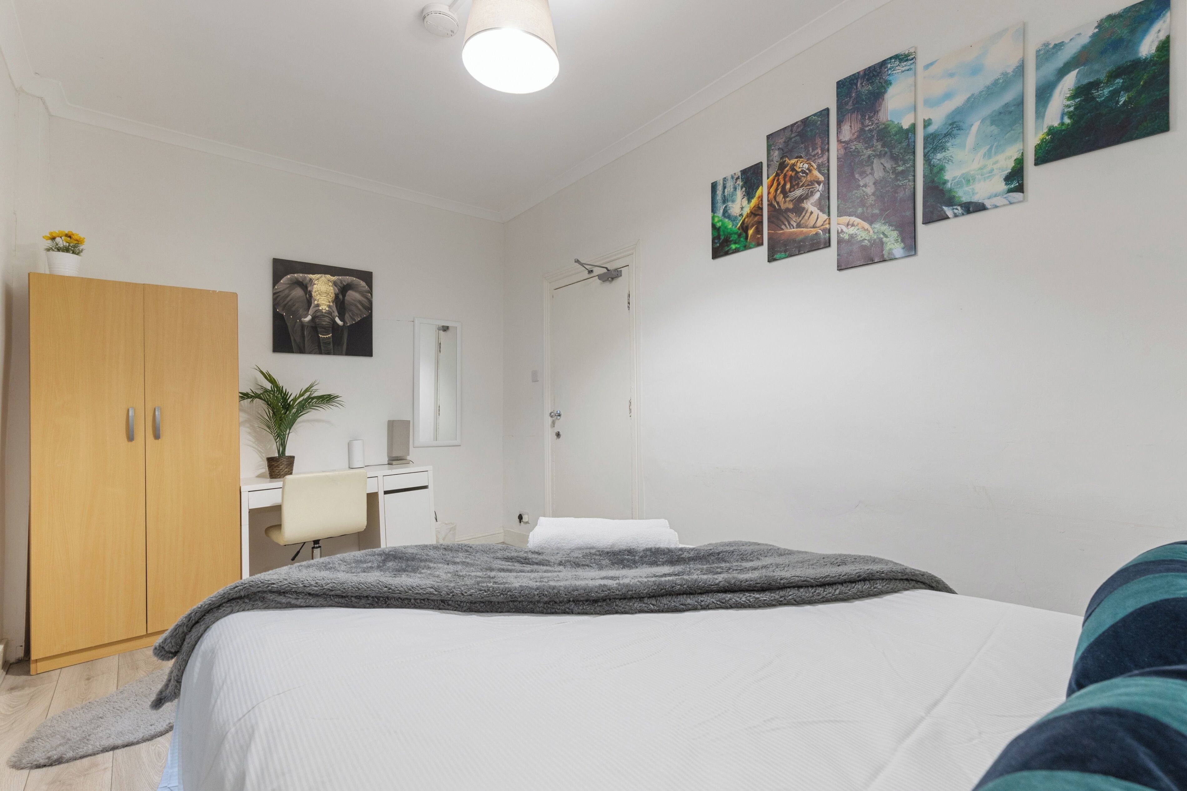 Ein Schlafzimmer mit Bett, Schreibtisch, Kleiderschrank und Dusche.