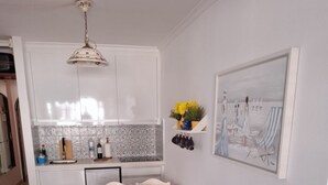 Ein kompakter Wohnbereich mit Küchenzeile, Essbereich und Sitzecke mit Sofa und Kissen.