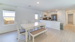 A spacious kitchen with white cabinetry, a dining area with a white table and chairs, and a small island with a sink. - 7 Mi to Alamo Ranch Mall: Home w/ Large Yard! (San Antonio)