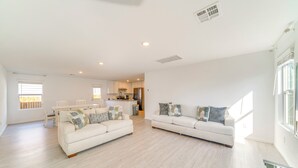 A spacious living area with two white sofas, a dining table, and a kitchen in the background. - 7 Mi to Alamo Ranch Mall: Home w/ Large Yard! (San Antonio)