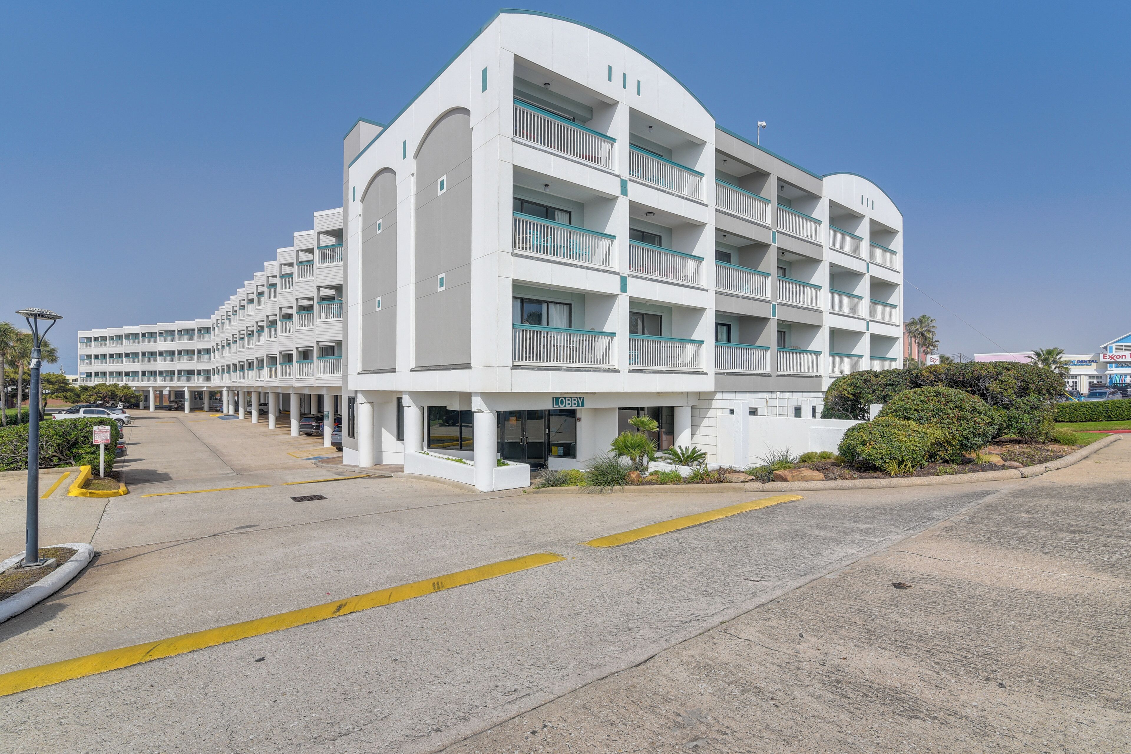 A multi-story hotel with a white facade, balconies, and a clear sky.
