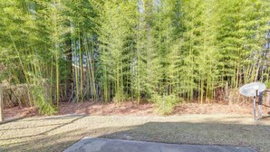 A concrete patio area with a metal sign, surrounded by bamboo and other vegetation. - Easy Access to I-77 & I-20: Columbia Duplex! (Columbia)