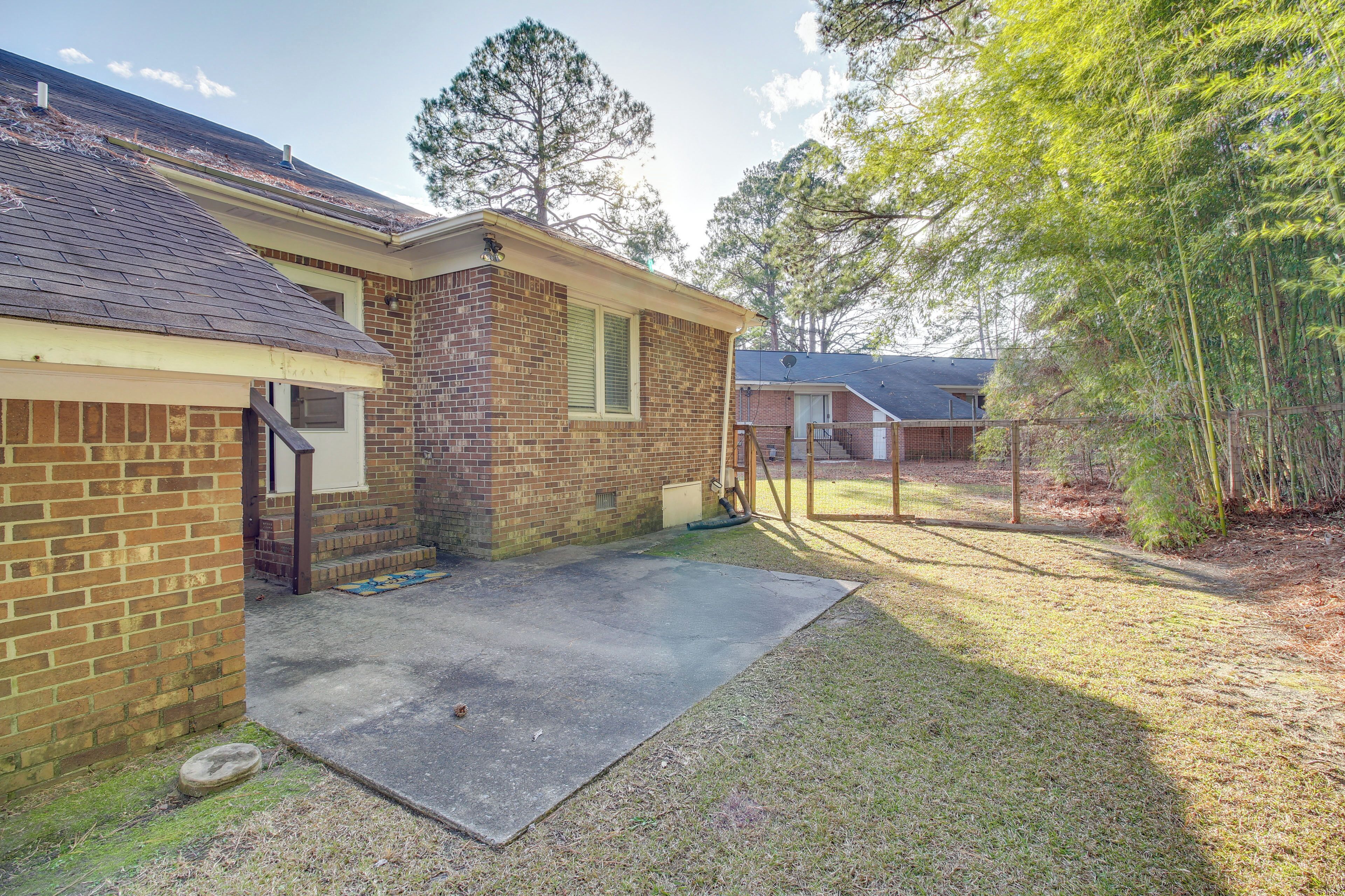 A residential property with a brick house, a covered patio, and a fenced yard.