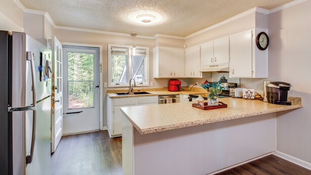 A kitchen with white cabinets, a stainless steel refrigerator, a red coffee maker, and a clock on the wall. - Easy Access to I-77 & I-20: Columbia Duplex! (Columbia)