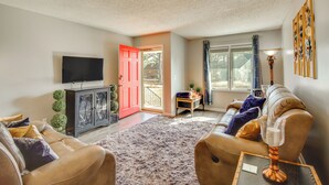 A living room with a sofa, a television, a cabinet, and a red door. - Easy Access to I-77 & I-20: Columbia Duplex! (Columbia)