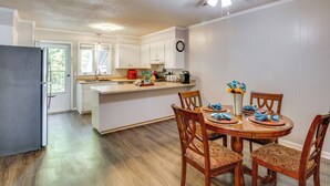 A modern kitchen with white cabinets, a wooden dining table set with blue napkins, and a ceiling fan. - Easy Access to I-77 & I-20: Columbia Duplex! (Columbia)