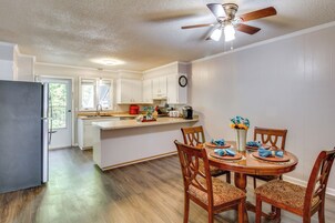 Una cocina moderna con armarios blancos, una mesa de comedor de madera con servilletas azules, y un ventilador de techo.