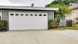 Et moderne hus med stor garageport, stenfacade og velholdt græsplæne.