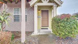 A house with a front porch, a door, and a small garden area with plants and a gravel path. - Walk to Lincoln City Beach: Townhome w/ Balconies! (Lincoln City)