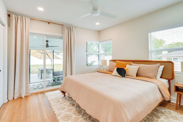 A bedroom with a large bed, a ceiling fan, and a view of the outdoors through a sliding glass door. - Mid-century Lakeland Home w/ Game Room! (Lakeland)