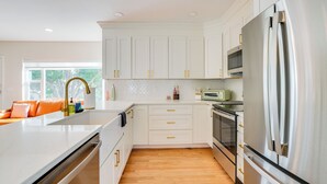 A modern kitchen with white cabinets, stainless steel appliances, and a wooden floor. - Mid-century Lakeland Home w/ Game Room! (Lakeland)