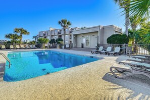 A swimming pool with lounge chairs and a building with balconies. - Waterfront Gem w/ Balcony in Garden City (Murrells Inlet)