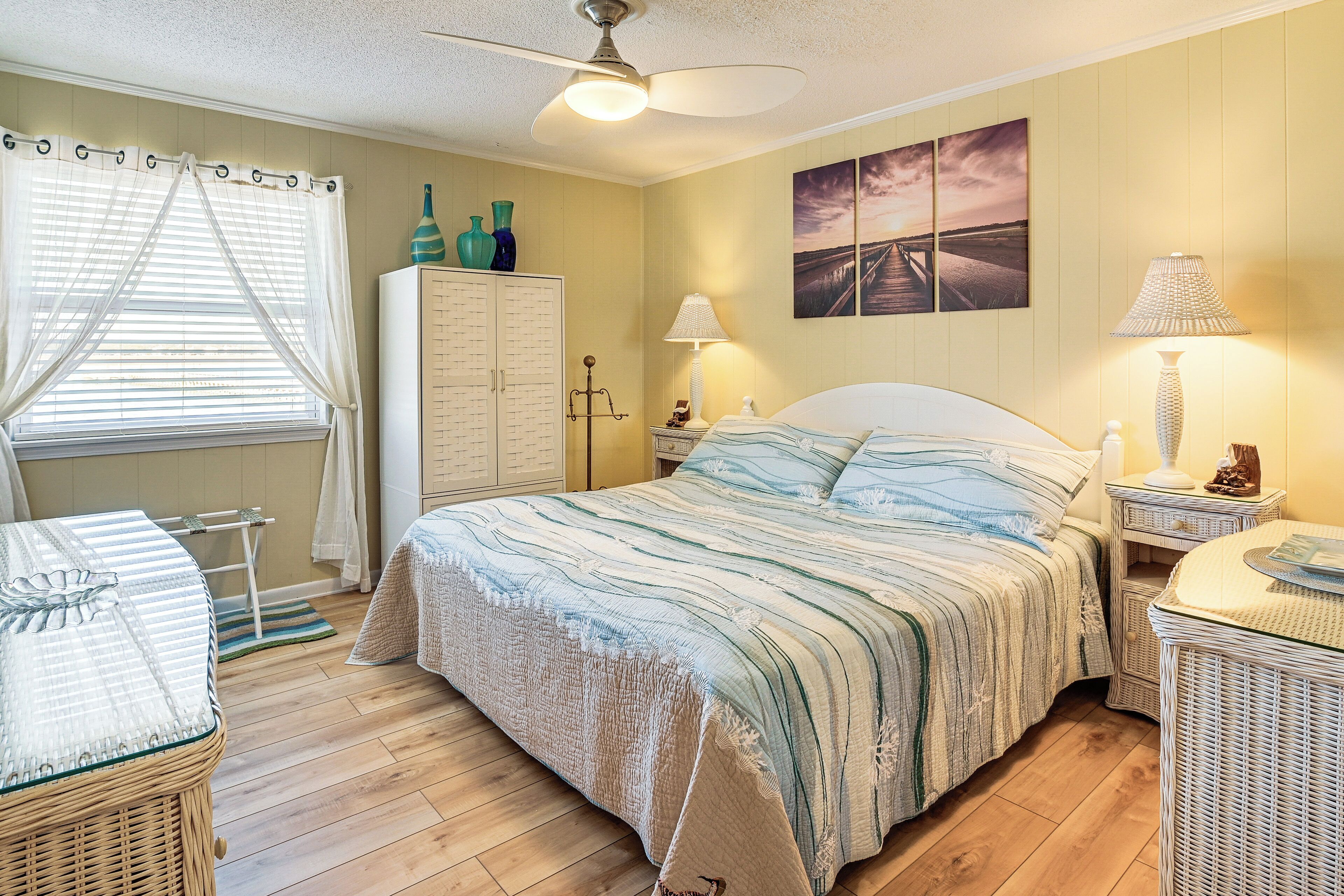 A bedroom with a bed, a wardrobe, a nightstand, a lamp, and a window with curtains.