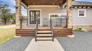 Une maison dotée d’un porche abrité, de piliers en pierre et d’un escalier menant à l’entrée.
