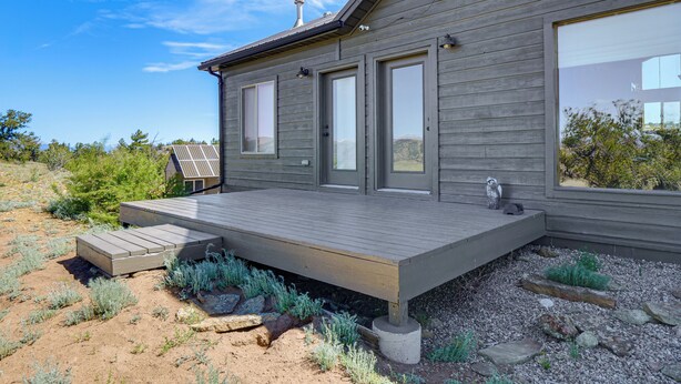 Ein modernes Haus mit Terrasse, großen Fenstern und einer Solaranlage.