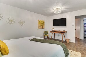 A bedroom with a bed, a desk, a chair, a television, and a painting on the wall. - Near Shops & Eats: Vinita Home w/ Furnished Patio (Vinita)