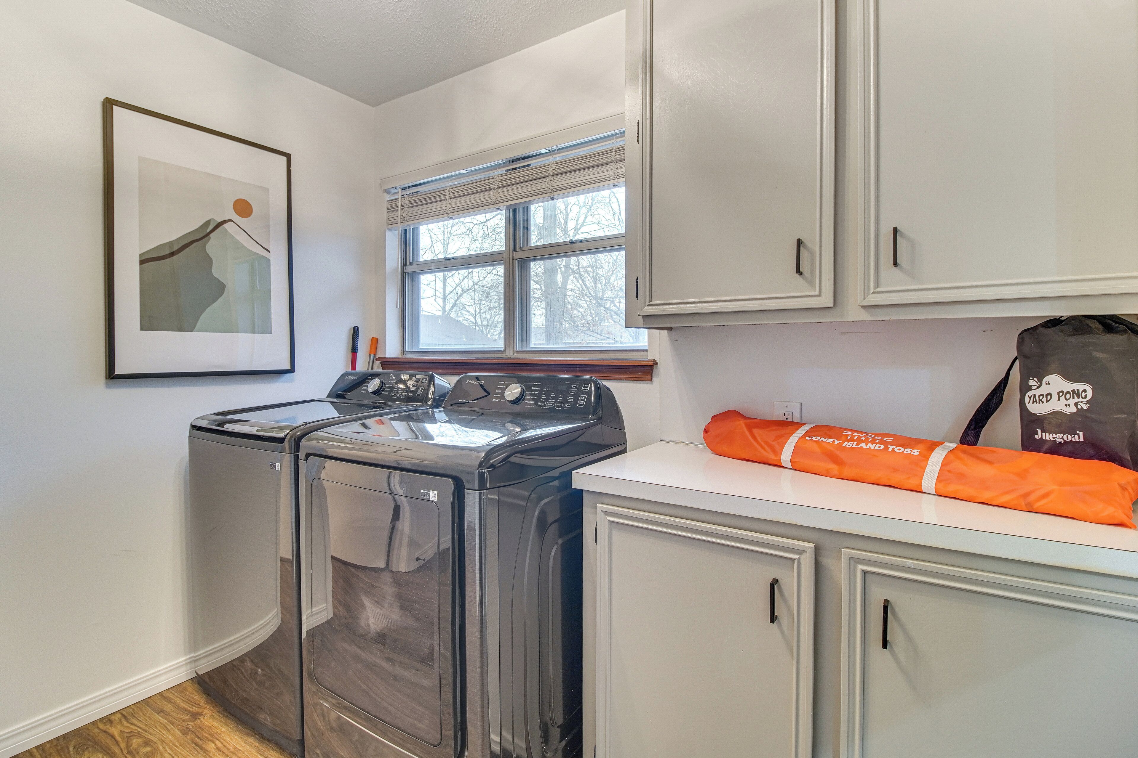 A laundry room with a washing machine, dryer, and cabinets.