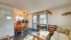 A living room with a sofa, a coffee table, and a dining area with chairs and a table.