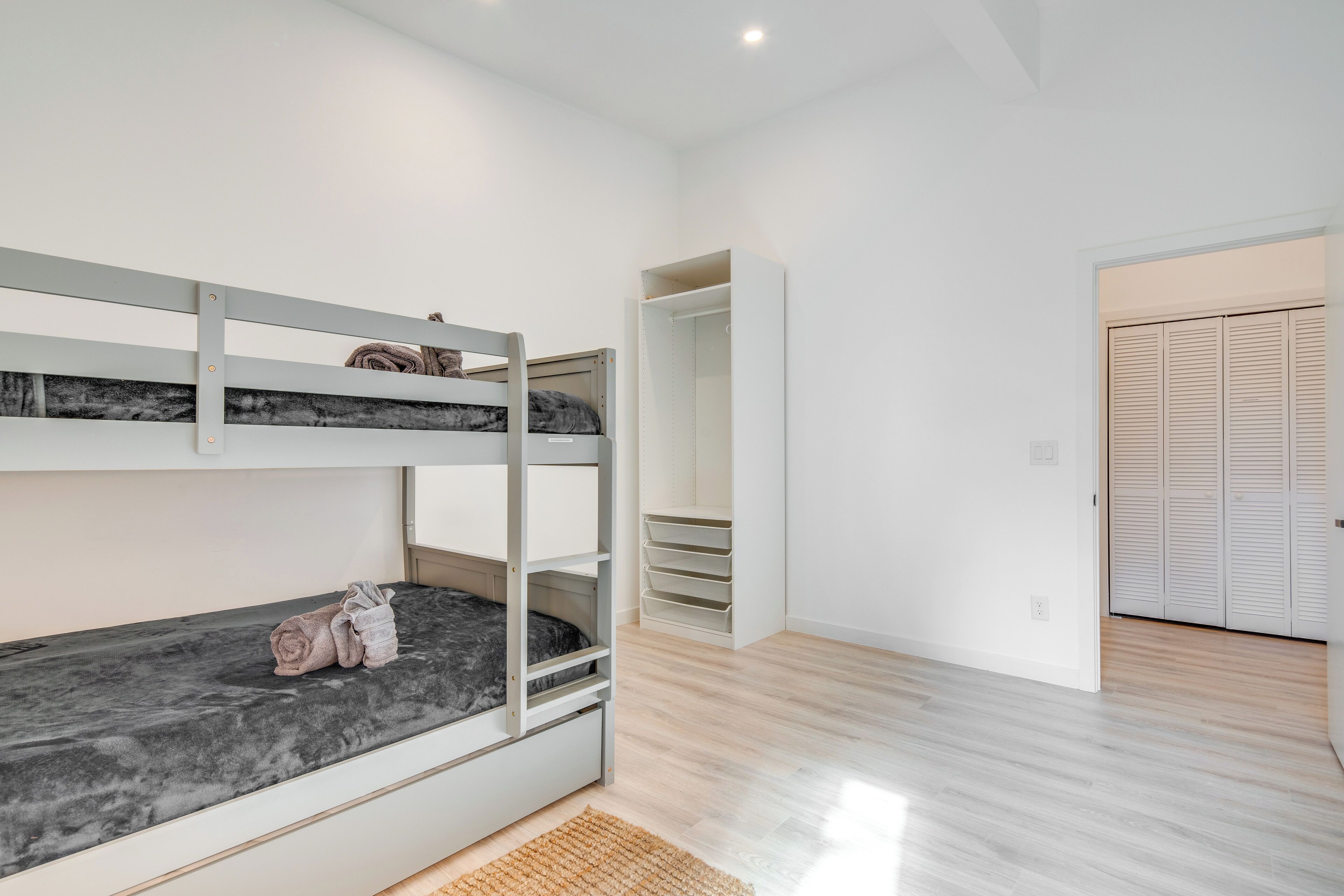 A room with bunk beds, a wardrobe, and a closet.