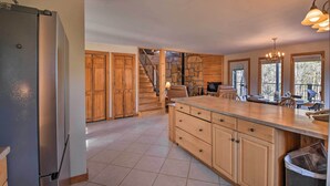 Un'ampia cucina con una grande isola, mobili in legno, piano cottura integrato e una parete decorativa in pietra.