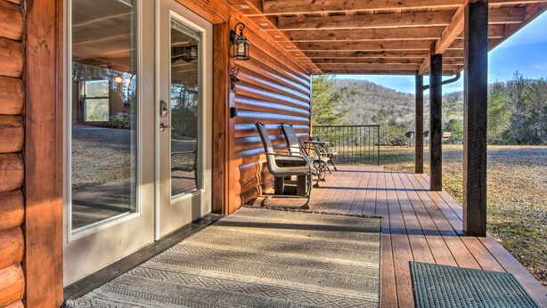 Una baita di legno con un portico coperto, una porta con pannelli di vetro e vista sul paesaggio circostante.