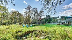 A lush garden with a pond, a gazebo, and a seating area with chairs. - Creekside Catskills Retreat: Deck, Bbq, & Firepit (Parksville)