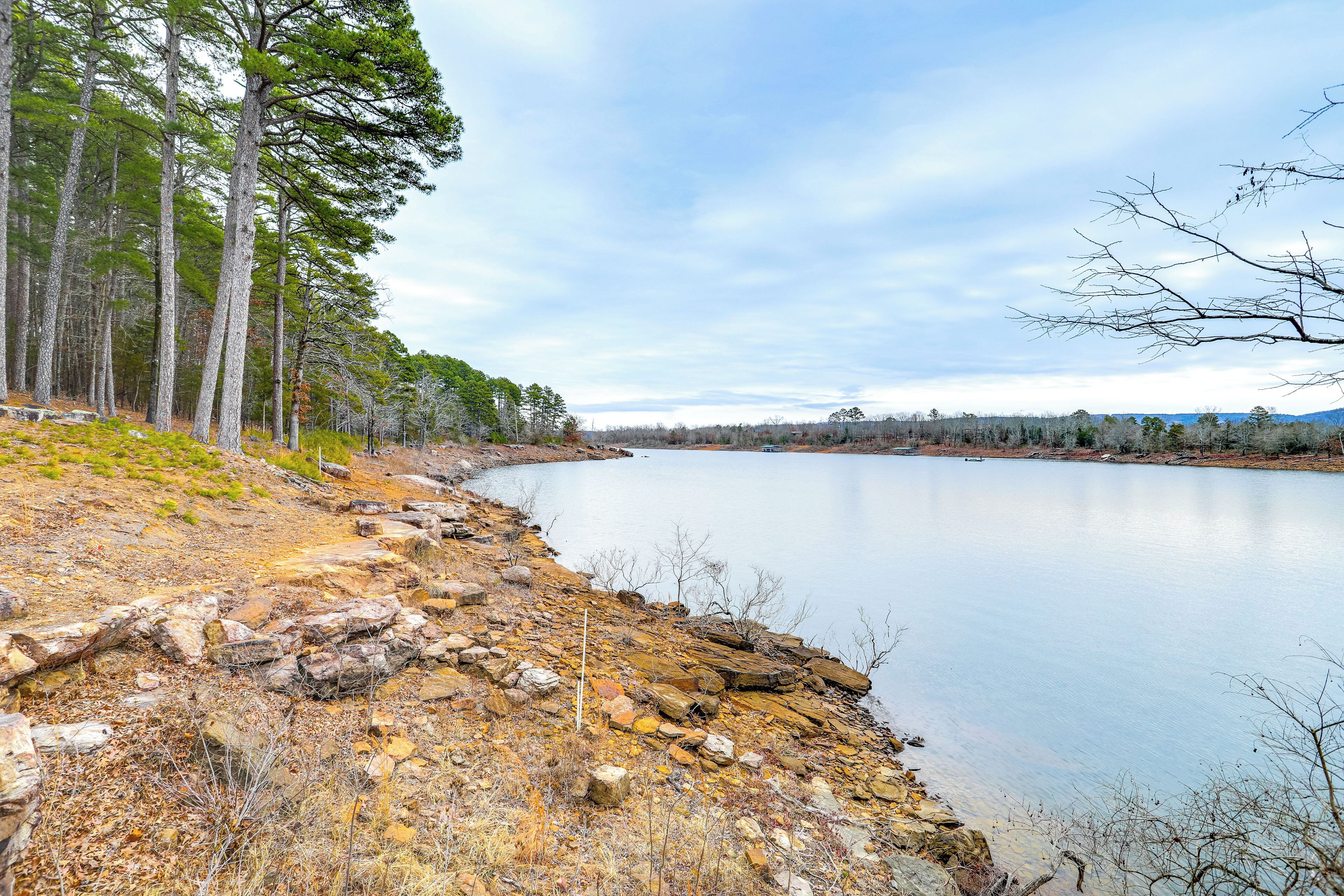 A lakeside view with rocky terrain and trees.