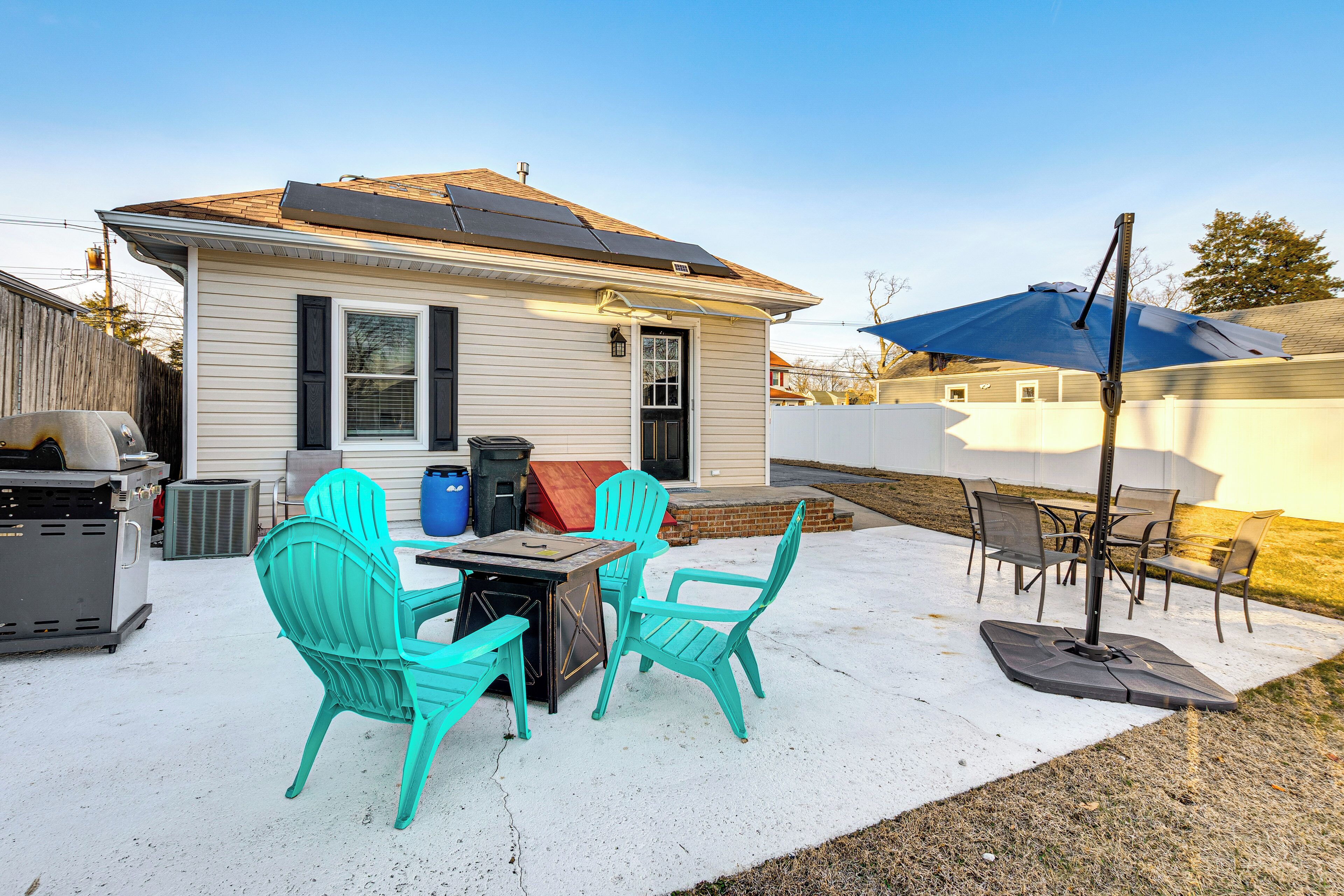 A patio with turquoise chairs, a table, and a blue umbrella.
