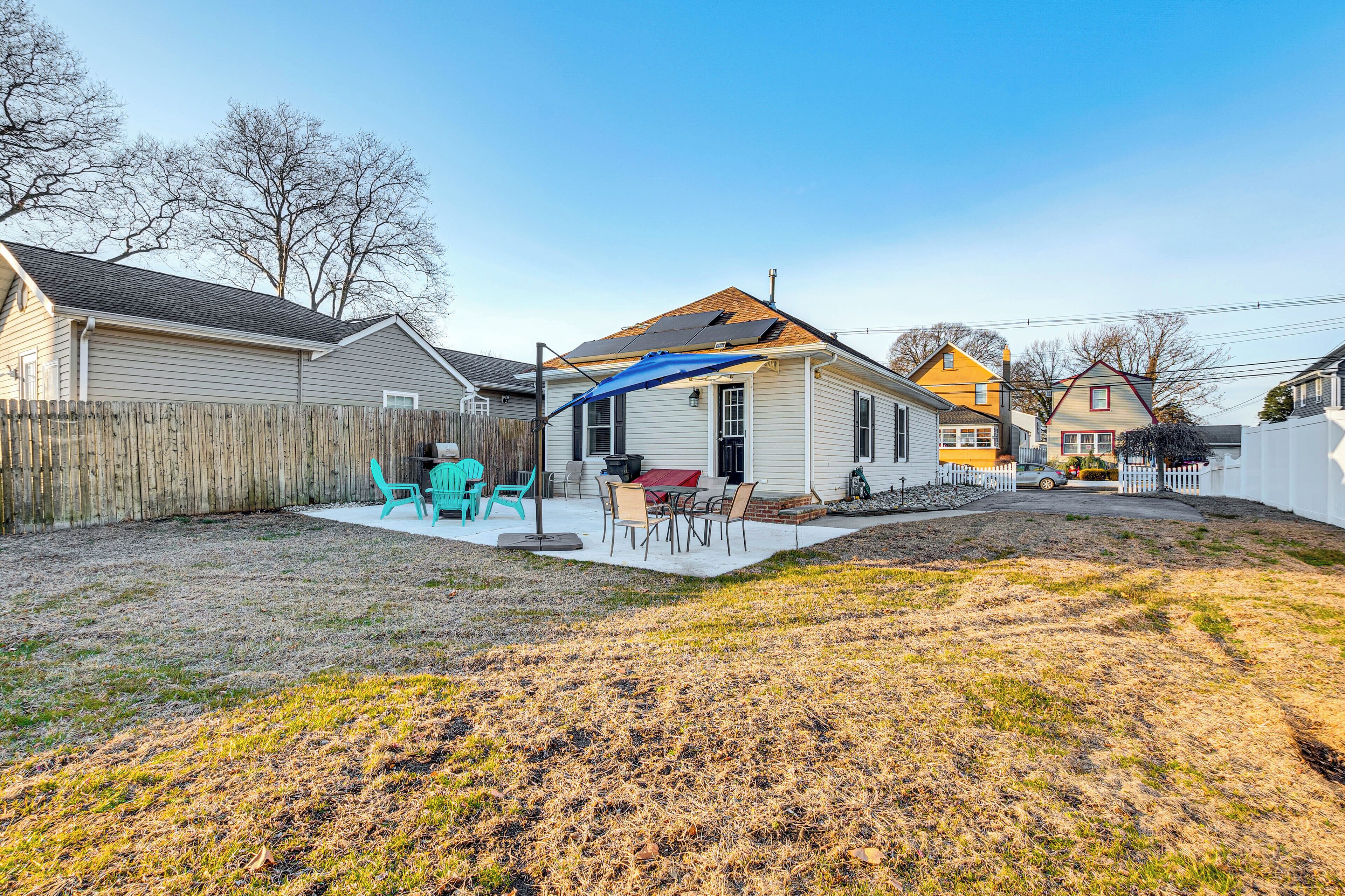 A residential backyard with a patio, outdoor seating, and a wooden fence.