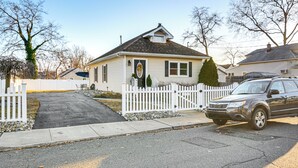 Una casa residencial con valla de piquetes blancos, entrada de vehículos y un SUV estacionado.