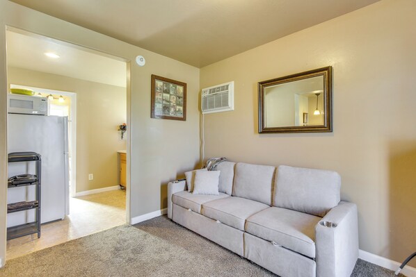 A living room with a beige sofa, a coffee table, a framed picture, and a mirror on the wall.