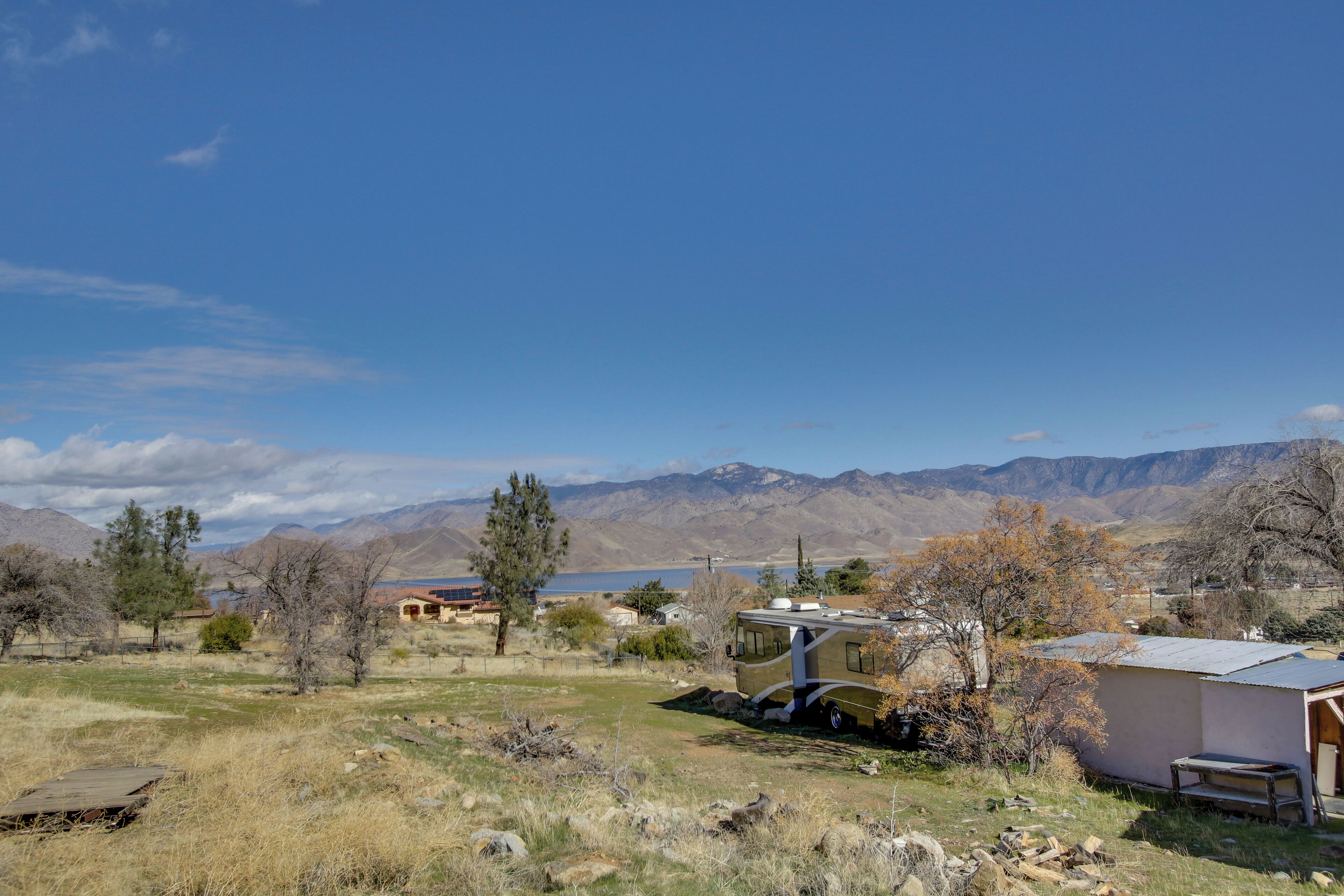 A remote RV campsite with a small building, a parked RV, and mountains in the background.