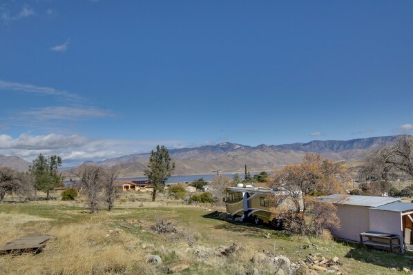 A remote RV campsite with a small building, a parked RV, and mountains in the background.