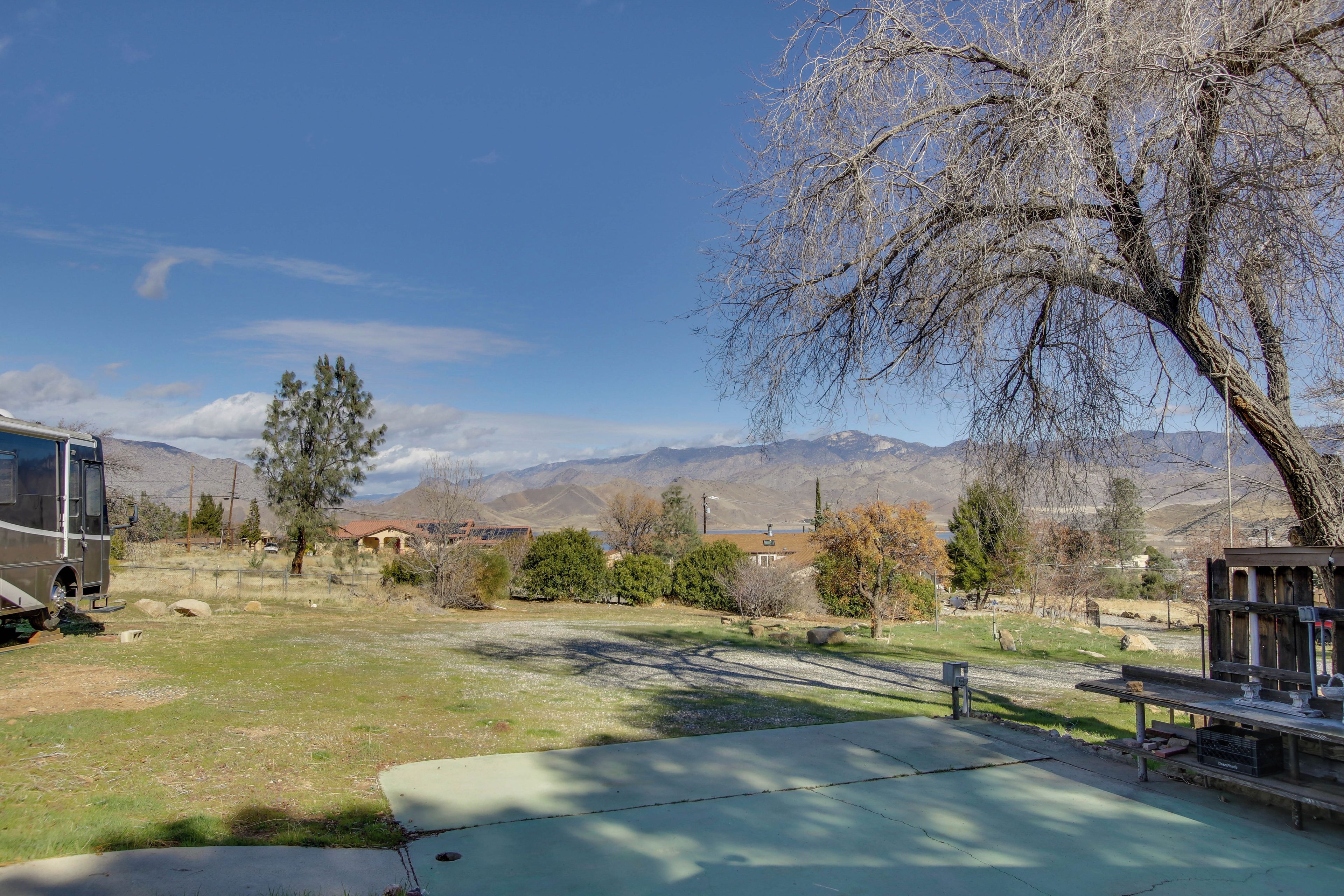 A residential area with a parked RV, a picnic table, and a large tree.